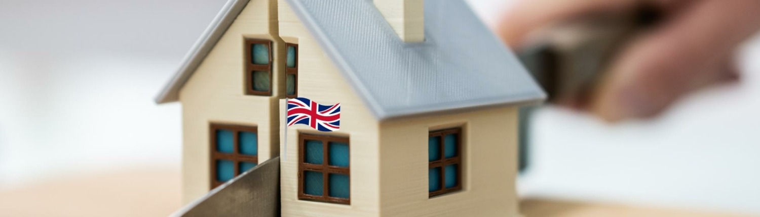 Divorce in England symbolized by house flying British flag being cut in half with knife