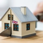 Divorce in England symbolized by house flying British flag being cut in half with knife