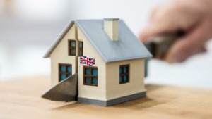 Divorce in England symbolized by house flying British flag being cut in half with knife